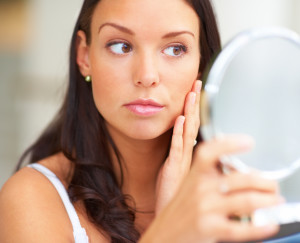 Woman looking at her face in mirror
